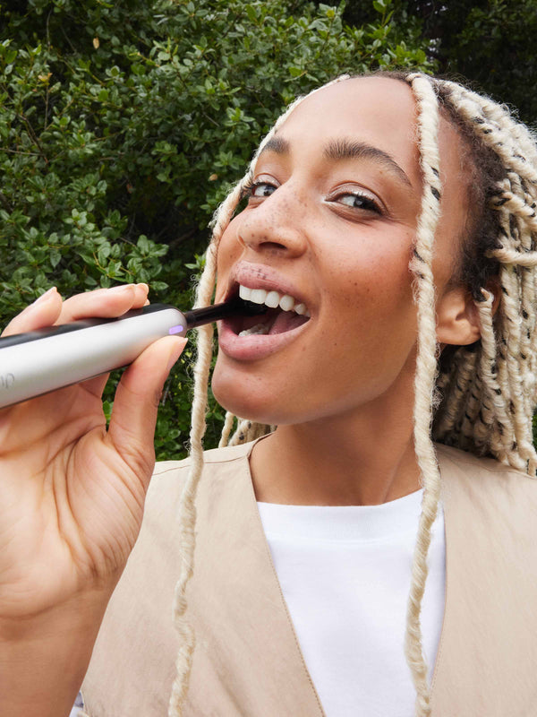 A model smiles while brushing her teeth with quip 360 oscillating electric toothbrush