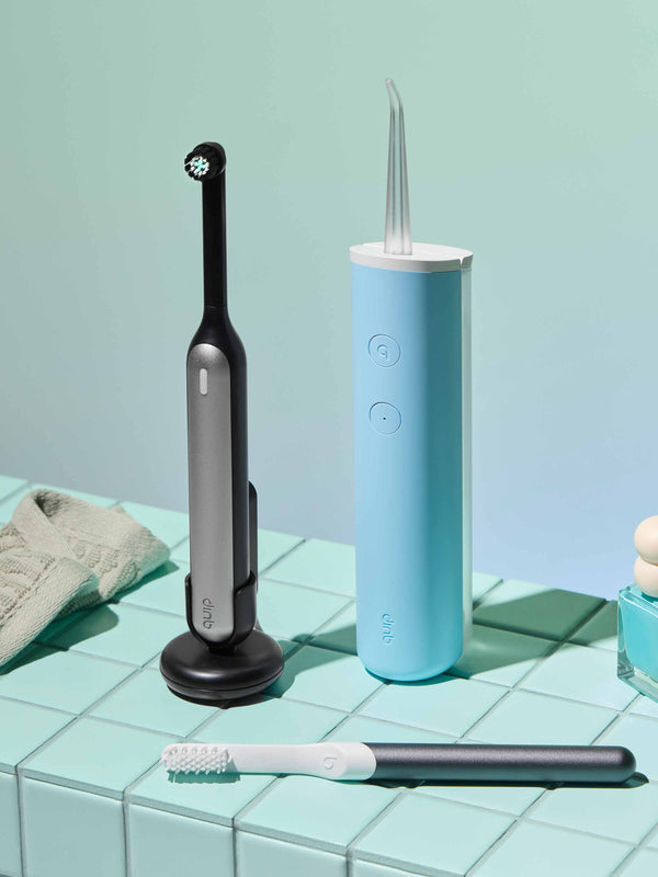 quip 360 oscillating toothbrush sits on a medicine cabinet shelf, along with a quip flosser and sonic toothbrush