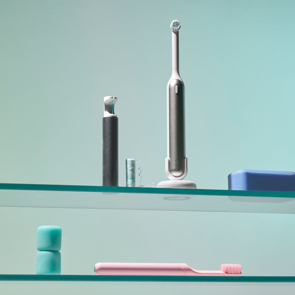 quip 360 oscillating toothbrush sits on a shelf with a quip floss string