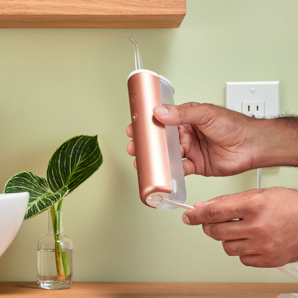 a model charging the quip rechargeable cordless water flosser in copper