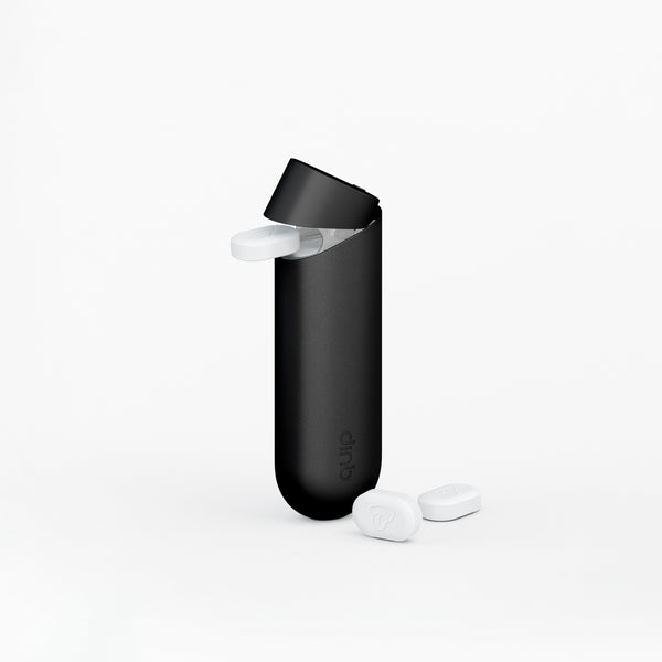 quip mint dispenser in black dispensing a piece of quip mint