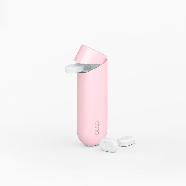 quip mint dispenser in pink dispensing a piece of quip mint