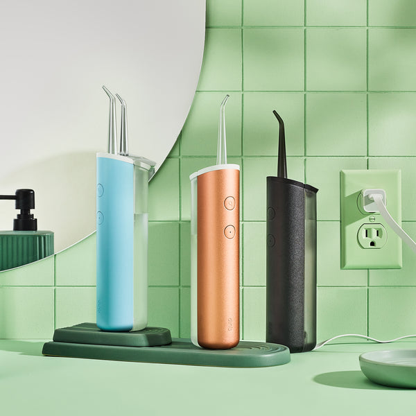 three quip Rechargeable Cordless Water Flossers sit on a bathroom sink