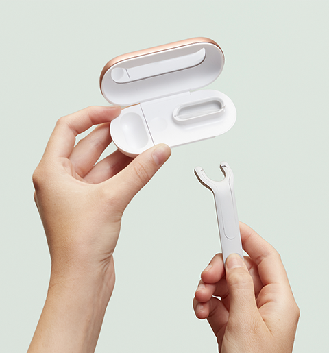Hands are holding quip's expanding floss pick refill opened to reveal a mirror inside, and strung to show how the pick will load the floss through a dispenser inside. 